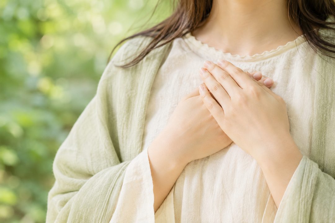 手のひらを胸に当てる女性